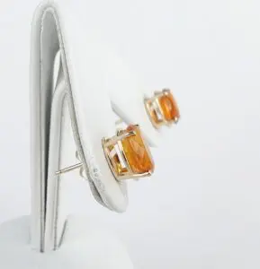 Amber gemstone earrings on white display stand.
