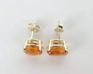 Gold earrings with orange gemstones.