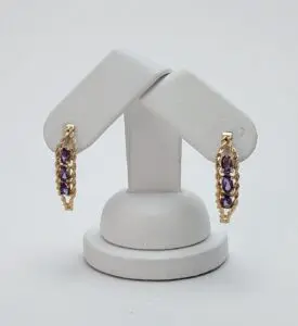 Gold earrings with purple gemstones on display.