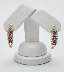 Gold earrings with purple gemstones on display.