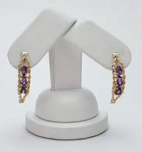 Gold earrings with purple gemstones on display.
