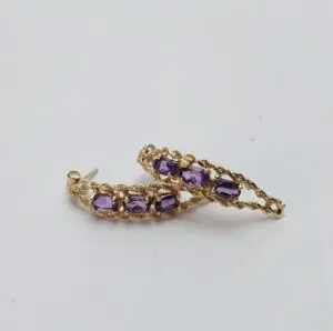 Gold earrings with purple gemstones on display.