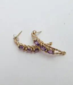 Gold earrings with purple gemstones on display.