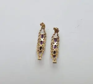 Gold earrings with purple gemstones displayed.