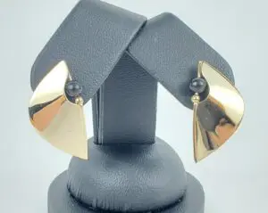 Gold earrings with black bead accents displayed.