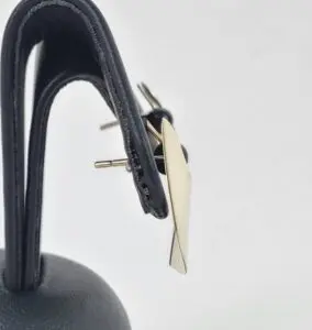 Gold earring on black leather display.