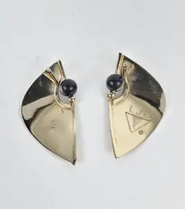 Gold earrings with black beads and engravings.