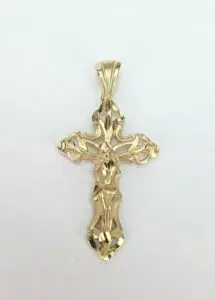 Ornate gold crucifix pendant on white background.