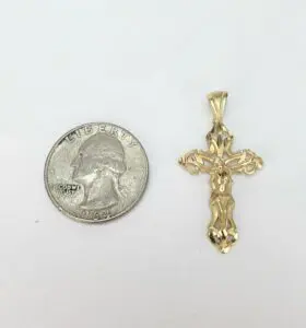Gold cross pendant beside a quarter coin.