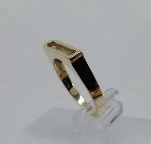 Gold geometric ring on clear stand.