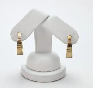 Gold earrings on a white display stand.