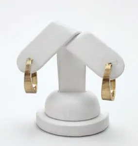 Gold hoop earrings on white display stand.