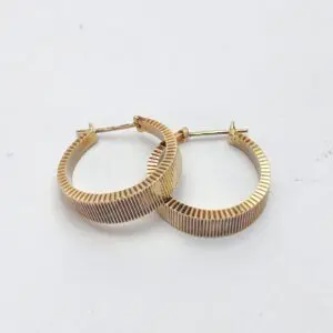 Gold textured hoop earrings on white background.