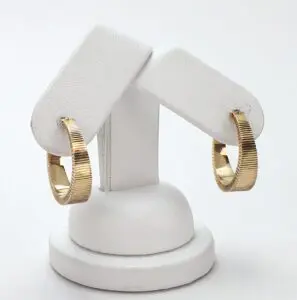 Gold hoop earrings on white display stand.