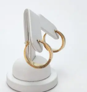 Gold hoop earrings on white display stand.