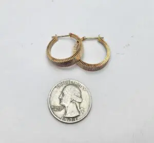 Gold hoop earrings beside a quarter coin.