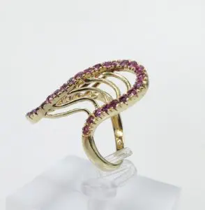 Gold ring with pink gemstones on display.