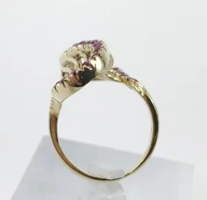 Gold ring with pink gemstones on stand.