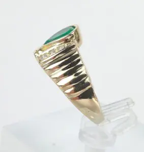 Gold ring with green gemstone on display.