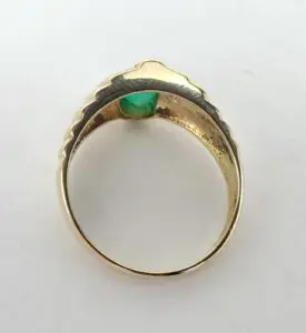 Gold ring with green gemstone under light.
