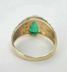 Gold ring with green teardrop gemstone inside.