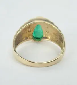 Gold ring with a green gemstone inside.