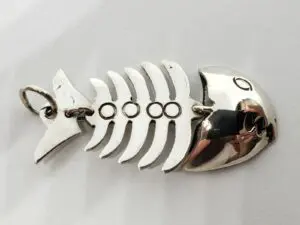 Silver fish skeleton keychain on white background.
