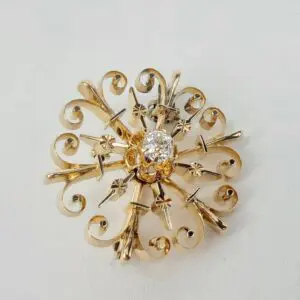 Gold brooch with intricate design and diamond.