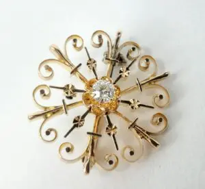 Ornate gold brooch with central diamond.