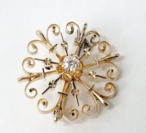 Ornate gold brooch with central diamond.
