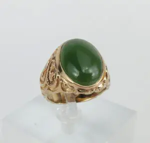 Gold ring with green gemstone on display.