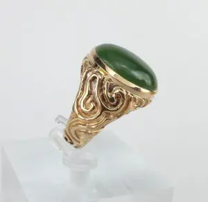 Gold ring with green stone and pattern.