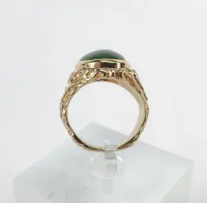 Gold ring with green stone on display.