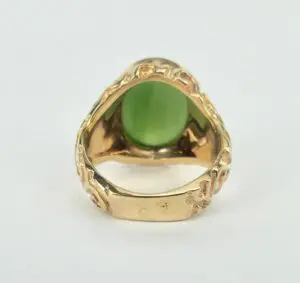 Gold ring with green gemstone, ornate design.