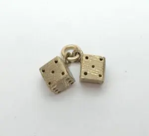 Two brass dice charms on ring.