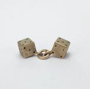 Two brass dice connected by ring.