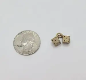Quarter beside two small dice charms.