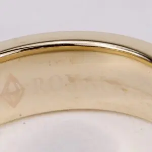 Gold ring with engraved text and symbol.