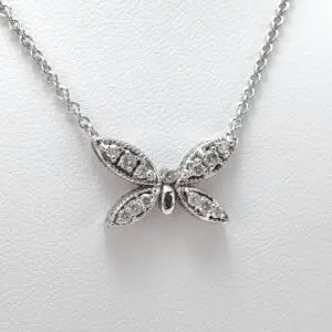 Butterfly-shaped silver necklace on white background.