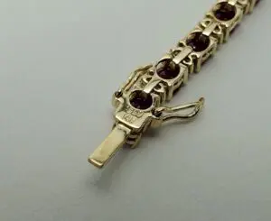 Gold bracelet with red gemstones clasp.