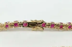 Gold bracelet with pink gemstones and clasp.