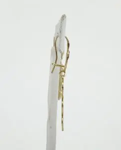 Gold dangling earrings on white stand.