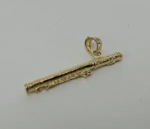 Gold flute-shaped pendant on white background.