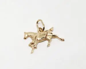 Gold horse pendant on white background.