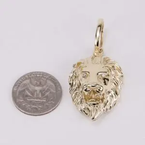Gold lion pendant beside a quarter coin.
