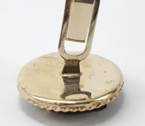 Gold cufflink with round base and clasp.