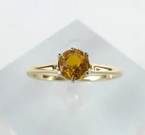 Gold ring with round yellow gemstone.