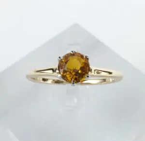 Gold ring with round yellow gemstone.