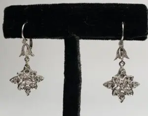 Silver floral earrings on display stand.