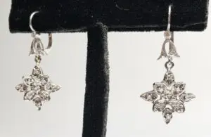 Silver star-shaped earrings on display stand.